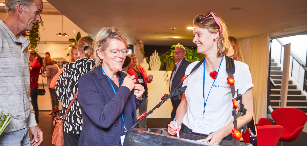 Impactadviseur Nienke Oosting draagt een bellytray of buikbak met hartjes die ze uitdeelt aan congresbezoekers tijdens een gesprek over impactgresdeelnemers en gaat met ze in gesprek over impact