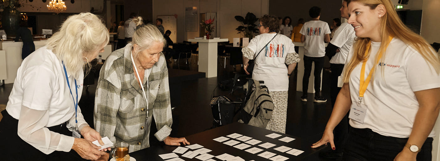 karin hoek en michelle kaper van de academie zijn aan de hand van kaartjes met rollen en competenties met een congresdeelnemer in gesprek over de kwaliteiten die bij een bepaalde functie horen