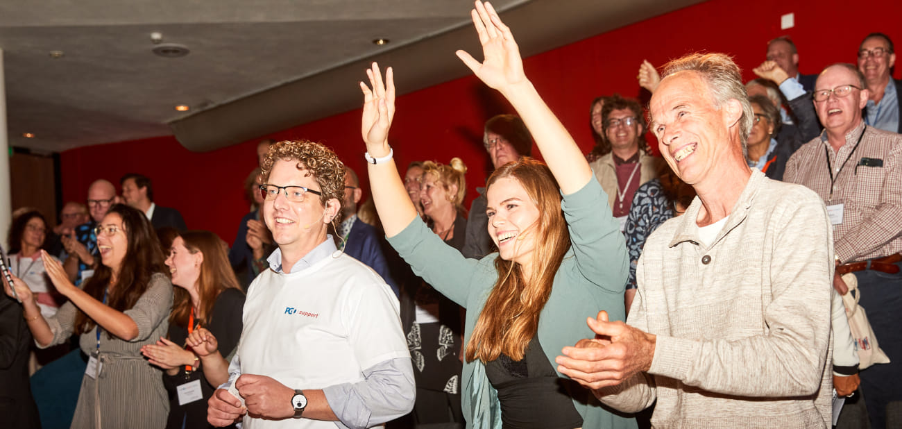 Het publiek in de zaal swingt enthousiast mee op de muziek tijdens een muzikaal intermezzo tijdens het plenaire programma